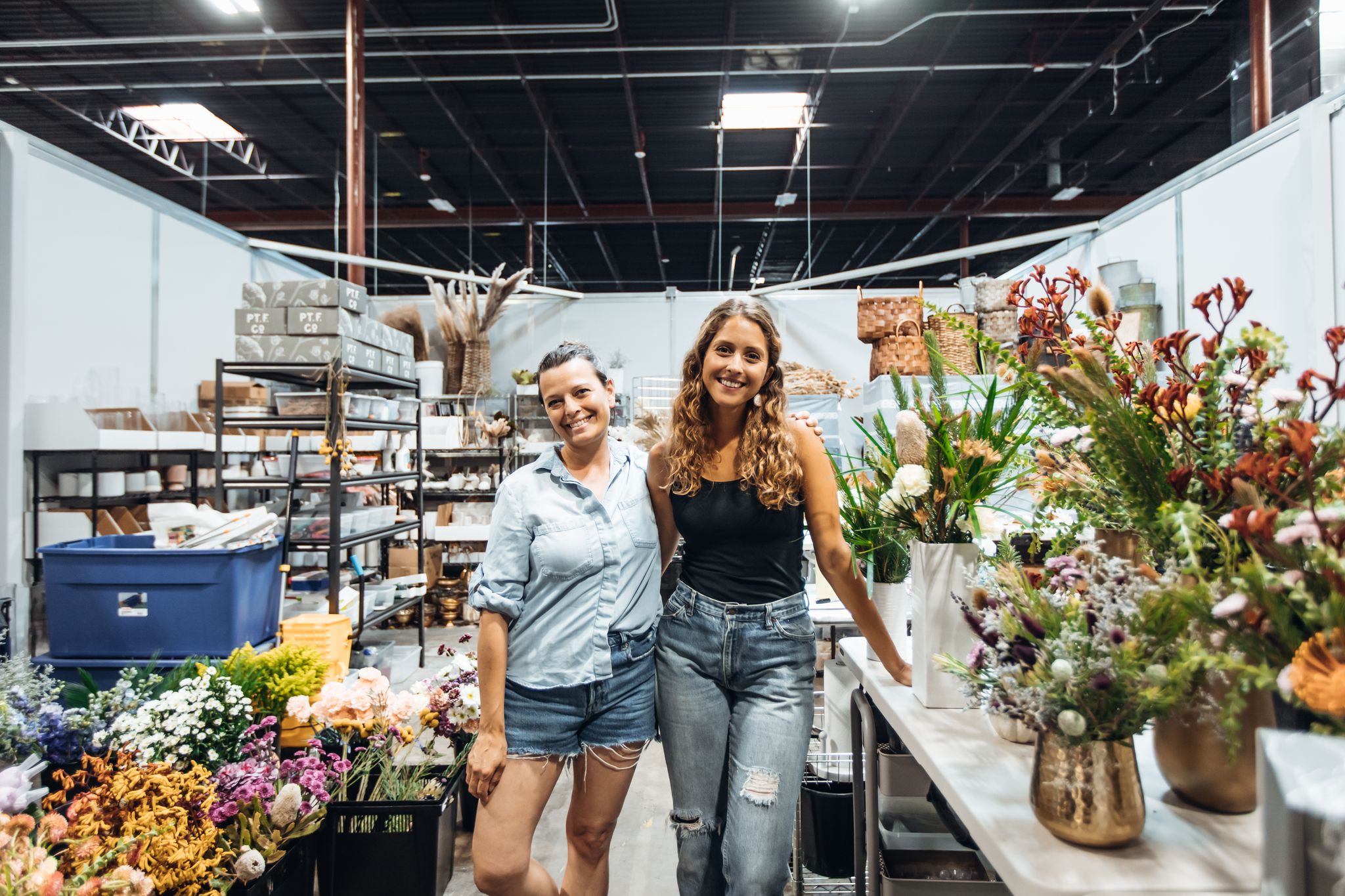 Two woman smiling, standing in flower shop